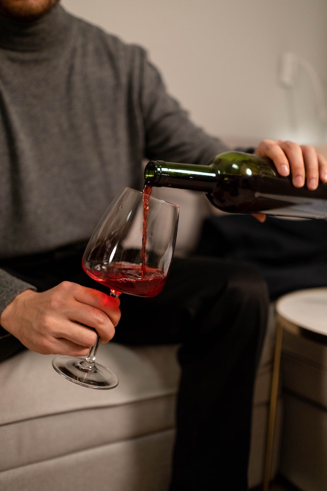 A person pouring red wine into a glass.