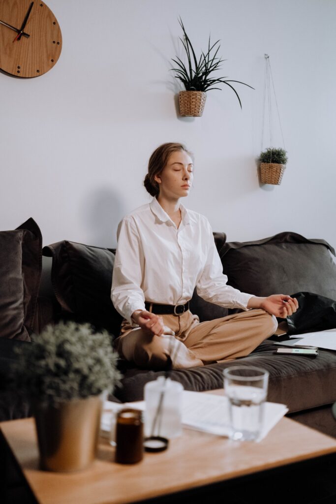 A woman meditating on a couch in her living room.