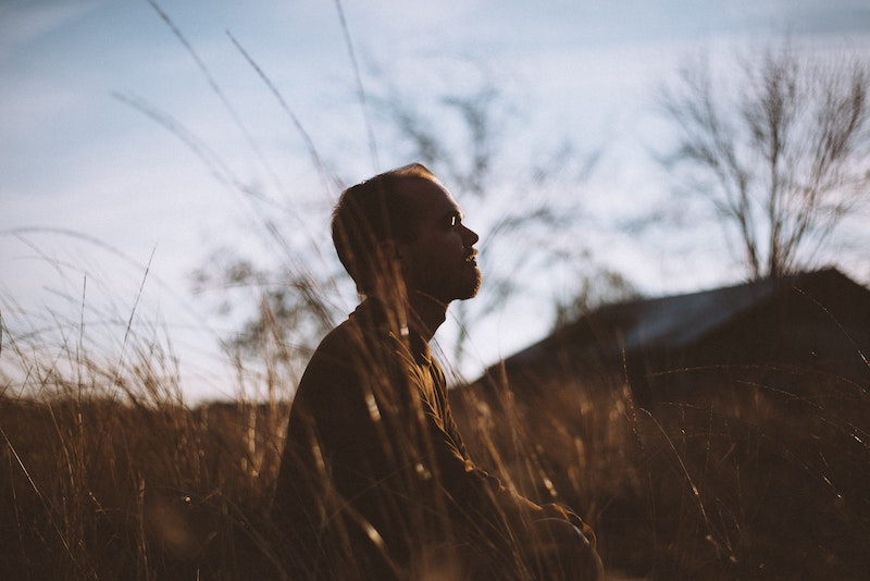 Man in field of tall grass looking up at sky.