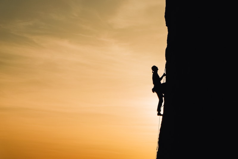 A silhouette of a woman climbing mountain