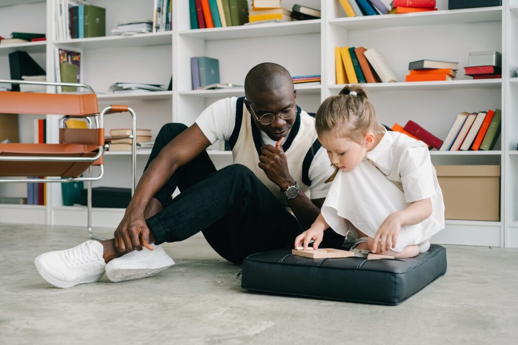 A man and a girl sitting on the floor playing a game.