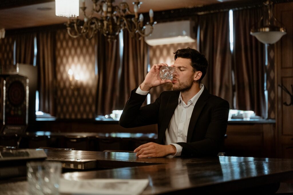 Man in suit drinking from a glass.