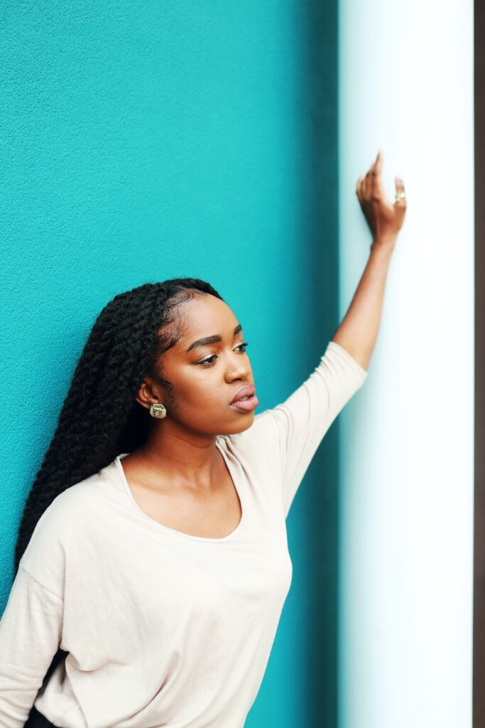 a girl in a white top with one hand on the wall