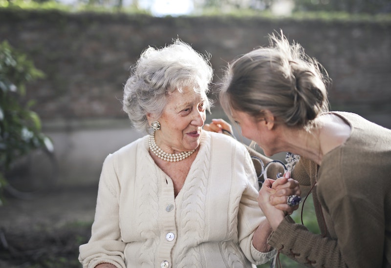 A woman is talking to an older woman in a garden.